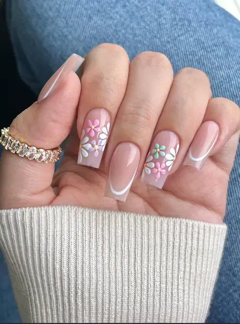 A unique spring nail design on long square nails, featuring a white French outline with accent nails showcasing a pastel floral petal design.