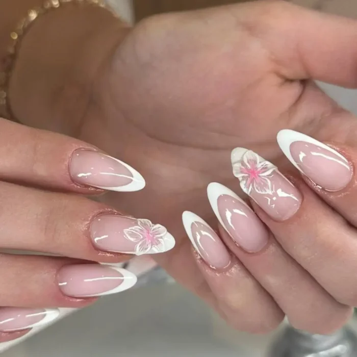 Almond French manicure with semi-translucent, frosted pink 3D flower accents.