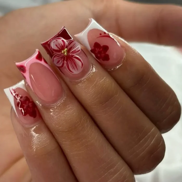 Square-shaped nails with a modern French manicure, featuring deep red floral designs and a 3D red flower accent.
