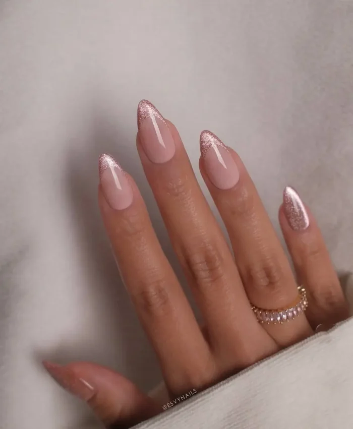 Nude nails with glamorous rose gold glitter on the tips, creating a modern and sparkling French manicure.