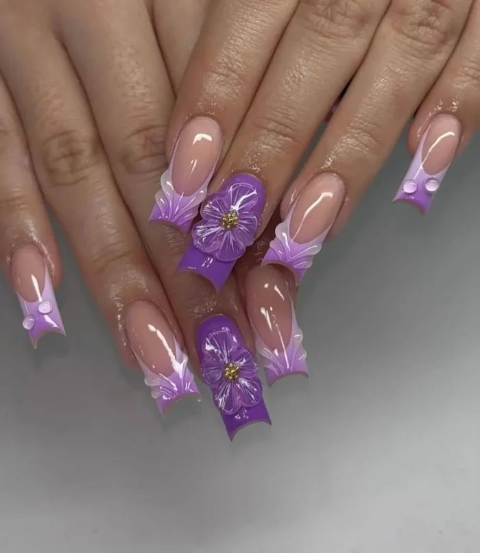Long flared nails with ruffled lavender tips, a sculpted purple nail design with oversized 3D flowers and water droplets.
