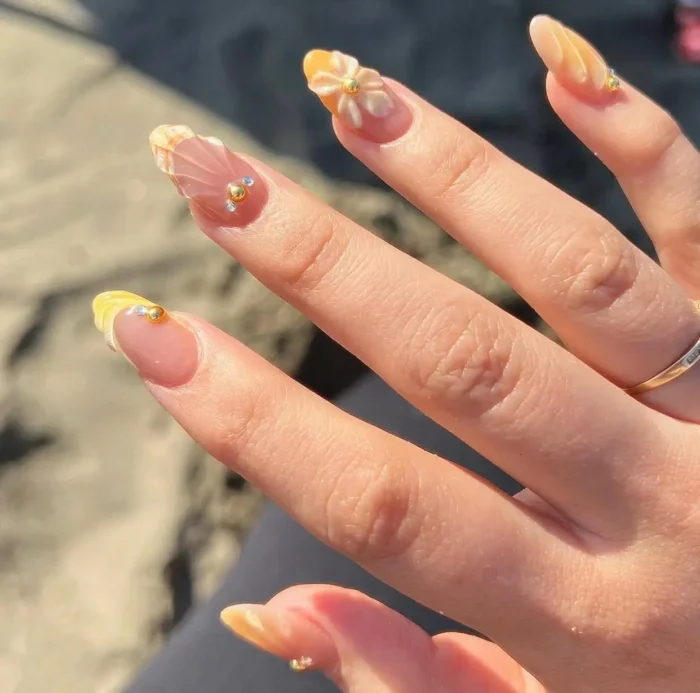 Short almond nails with a sunny summer look: textured yellow tips, 3D flowers, and gold bead accents.