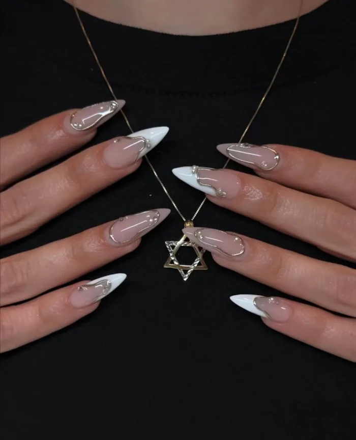 Long almond-shaped nails with a sharp white V-shaped French tip, dramatically accented with a dimensional, abstract liquid silver chrome design over the sheer base.