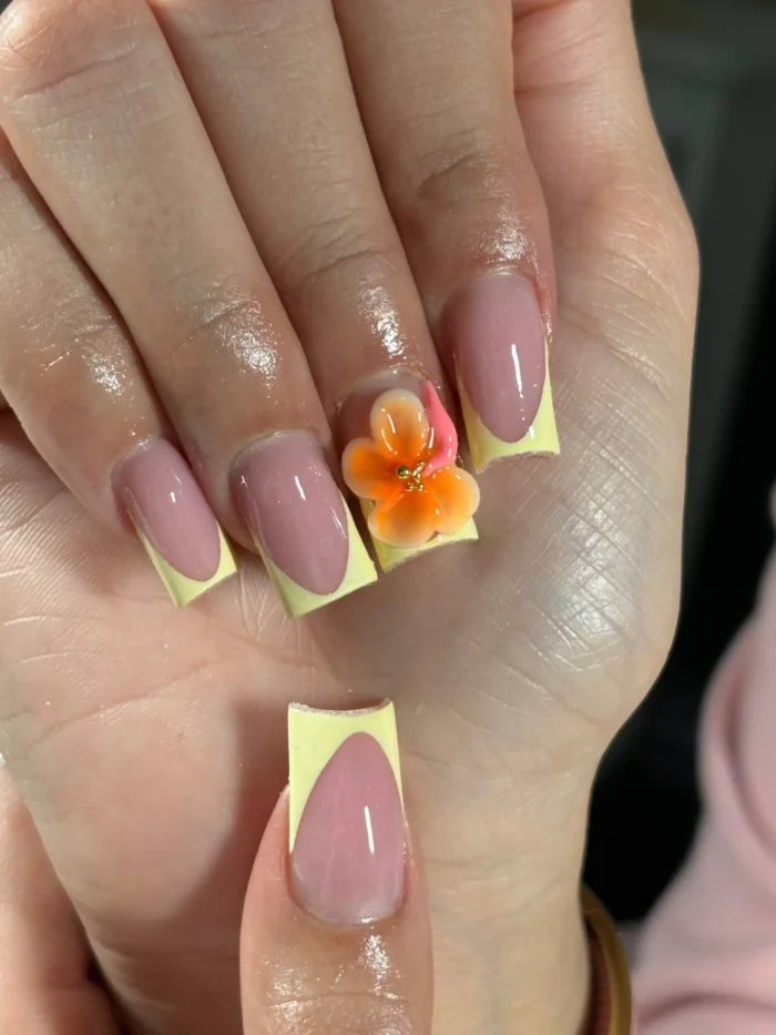 Medium square-shaped nails with pale yellow deep U-French tips, featuring a large 3D orange and yellow tropical flower accent.