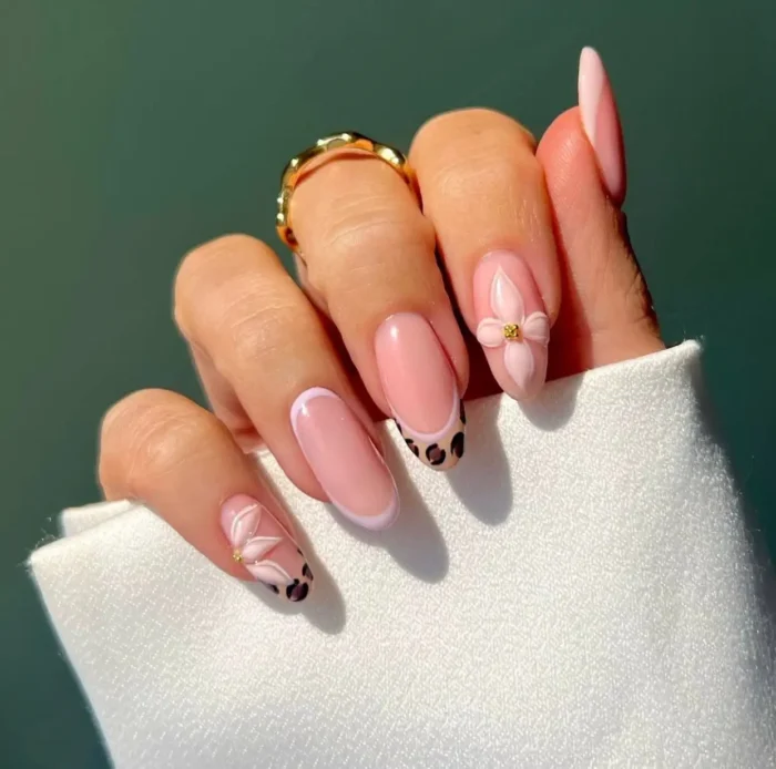 Modern summer nail design on oval nails: leopard print French tips with crisp white outlines and 3D pink flowers.