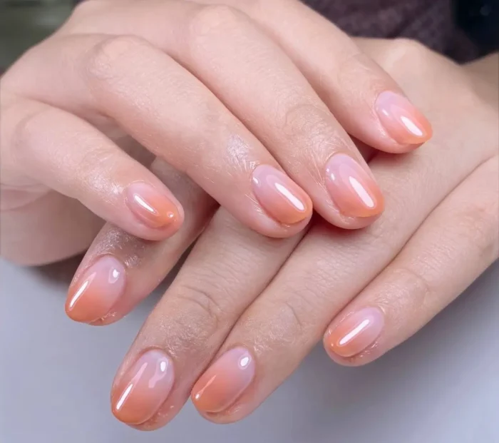 Cute simple gel manicure with a sweet peach sorbet and pink ombre blush effect on short to medium rounded nails.