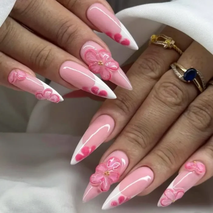 Long stiletto nails with a light pink base, white tips, and adorned with translucent 3D pink flowers and pink dot accents.