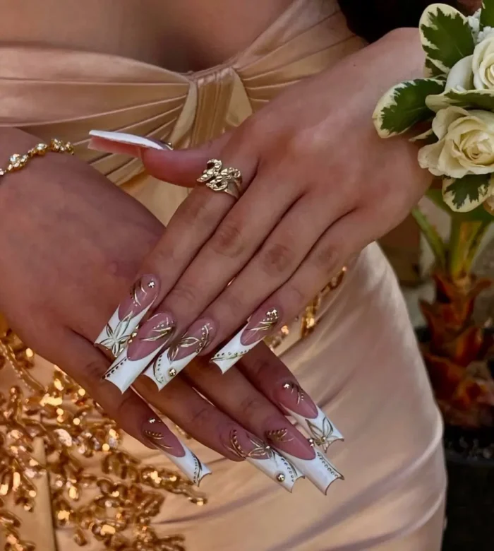 Long coffin nails with angular white French tips, adorned with intricate gold botanical linework and gold bead accents.