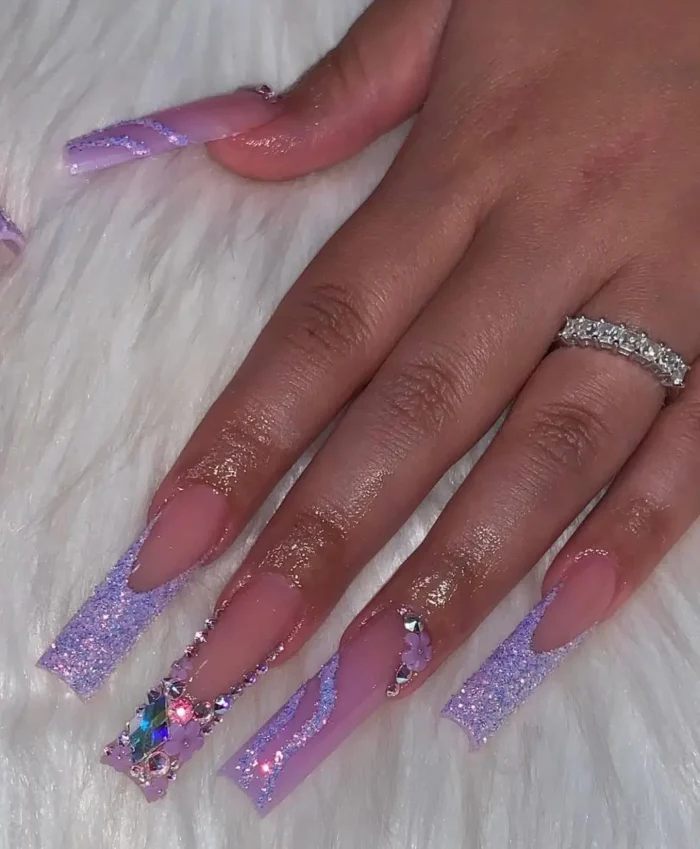 Ultra-long tapered nails with an ice queen lavender glitter nail design, heavily embellished with crystals and charms.
