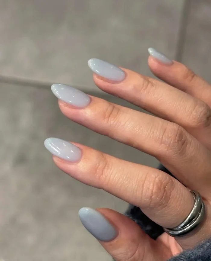 Cute simple gel manicure with a minimalist sheer grey-blue jelly finish on medium almond-shaped nails.