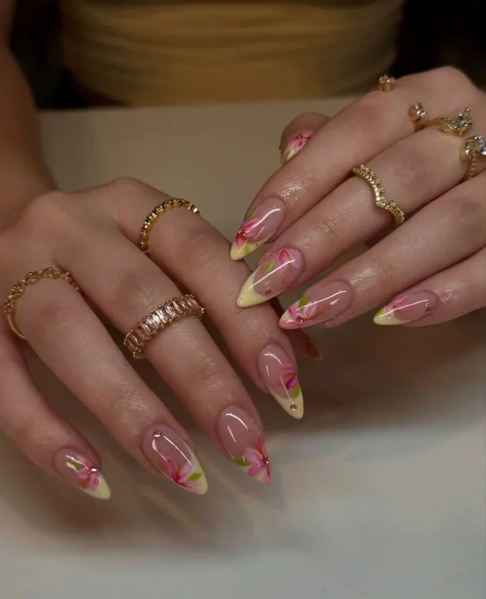 A vibrant, vacation-ready manicure with sunny yellow French tips and delicate, hand-painted tropical pink and orange flowers.