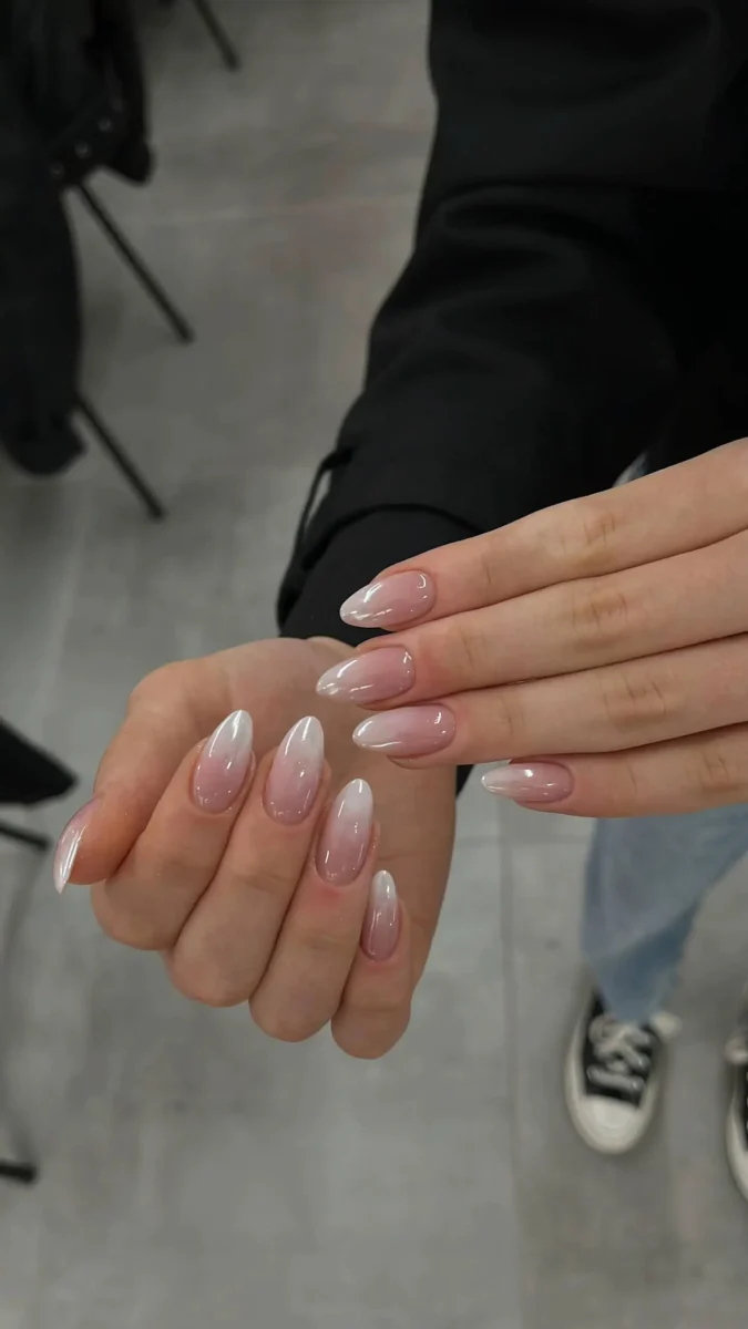 Medium almond-shaped nails showcasing a classic French ombré or 'baby boomer' effect, with a seamless blend from a sheer pink base to soft milky white tips.