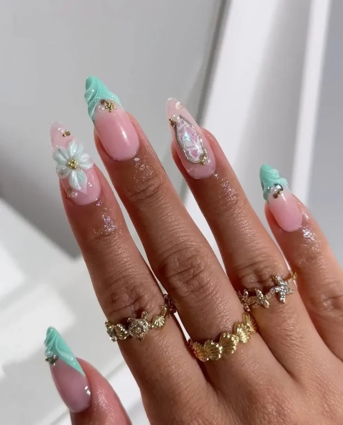 Refreshing summer nail design on long almond nails: sculpted mint green wave-like tips, 3D white flowers, and iridescent gem accents.
