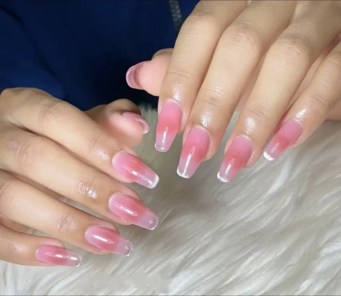 Cute simple gel manicure with a rosy pink jelly aura effect and clear tips on long squared coffin nails.