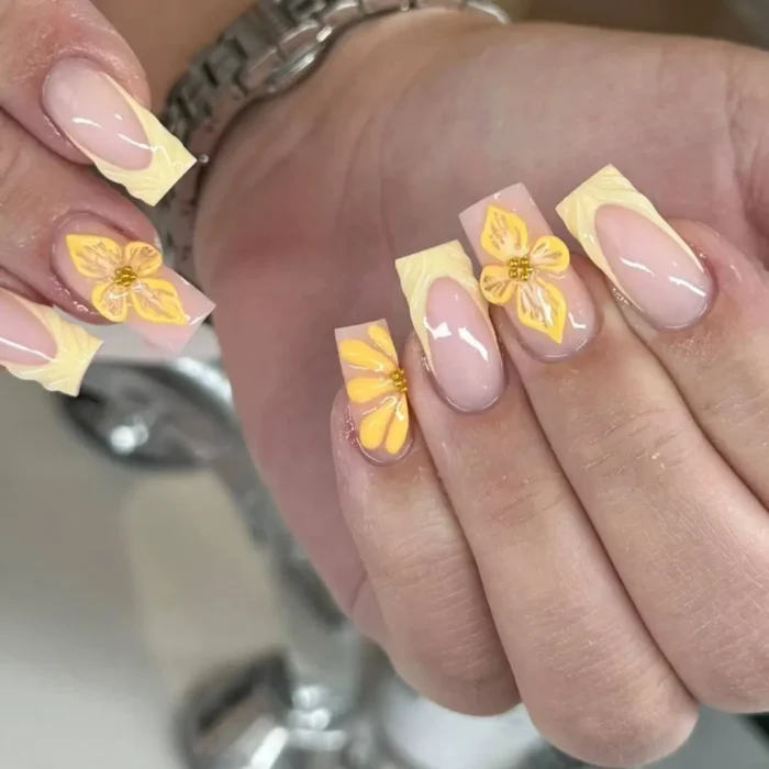 Long square nails with 3D pastel yellow sunflowers and textured, woven-style French tips.