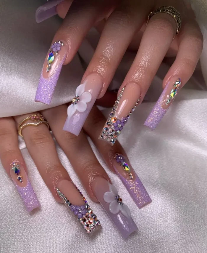 Square-tipped nails featuring a frosted lavender gems purple nail design with intricate 3D floral embellishments and sparkling rhinestones.