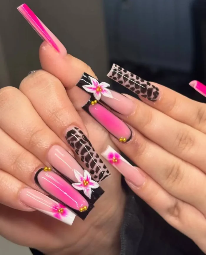Long square nails combining bright pink ombré, classic leopard print, and 3D pink and white floral accents with gold beads.