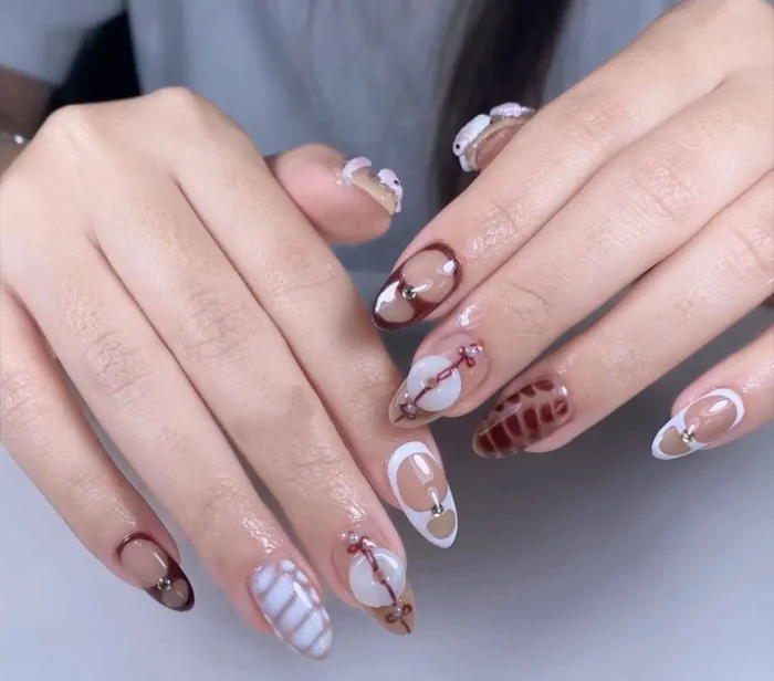 Almond nails with mixed designs in brown and cream, featuring textured woven patterns, quilted effects, abstract line art, and negative space elements.