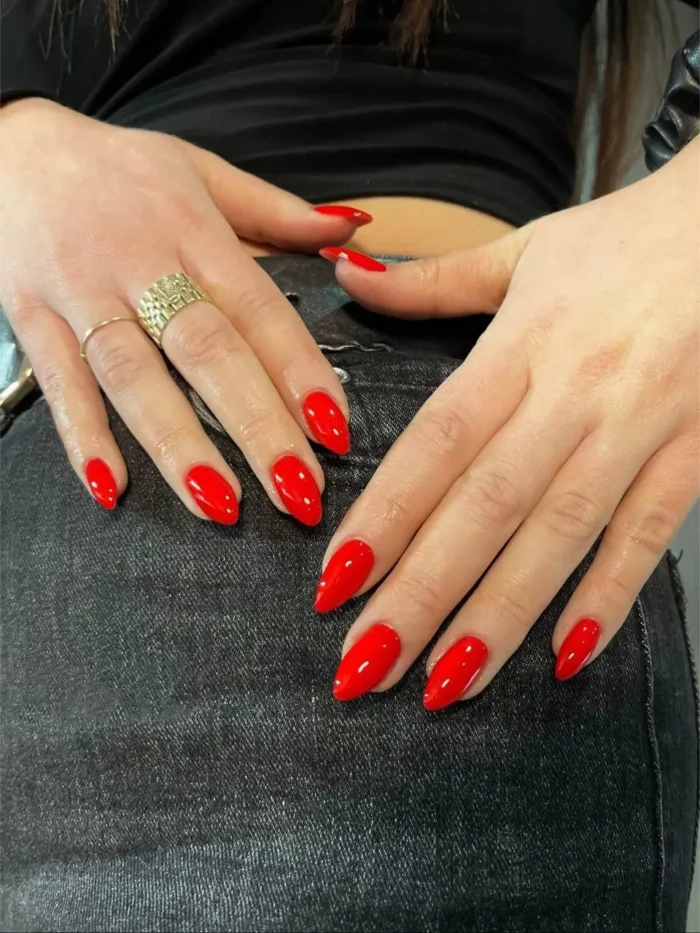 Cute simple gel manicure with a timeless fire engine red solid color on medium pointed almond nails.