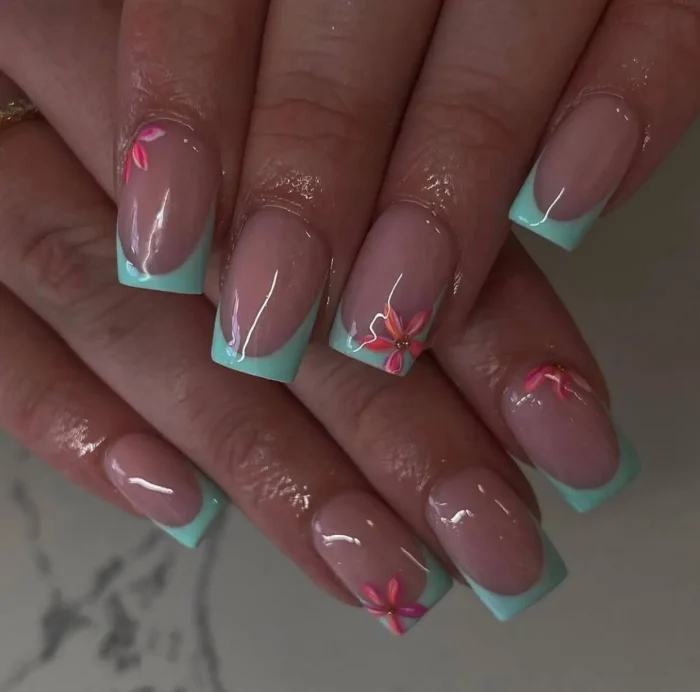 Short to medium square nails with a fresh minty-turquoise French tip, delightfully accented on some nails with a small, warm-toned pink or coral stylized flower with a gold center.