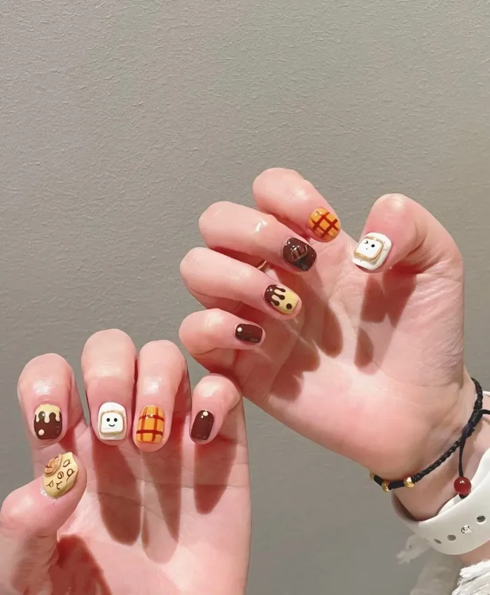 Very short square nails with cute breakfast and snack food designs like smiley toast, cookies, waffles, and dripping chocolate.