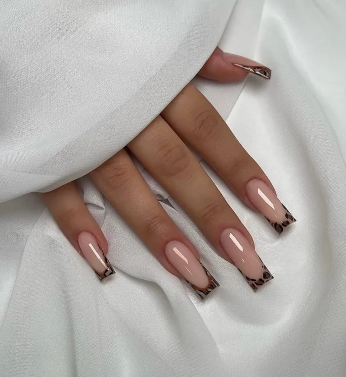 Long square or coffin-shaped nails showcasing a classic and chic leopard print French tip against a clean, sheer pink base.