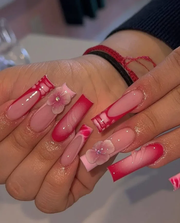 Elegant long nails with a soft pink base, vivid raspberry abstract tips, and 3D translucent pink floral accents with sparkling centers.