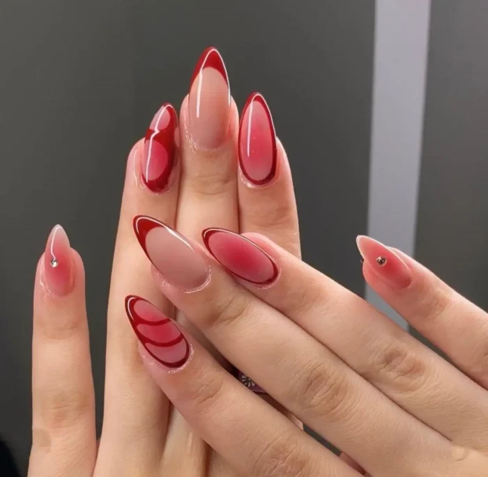 An artistic red nail design featuring a red aura effect on a nude base, framed with a dark red border.