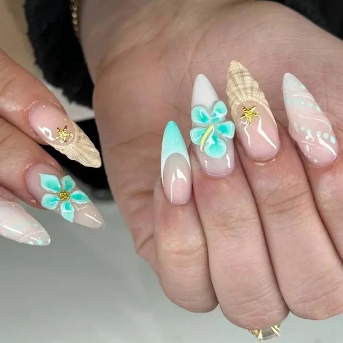 A mismatched, long stiletto manicure with 3D turquoise flowers, sandy-textured French tips, and seashell charms.