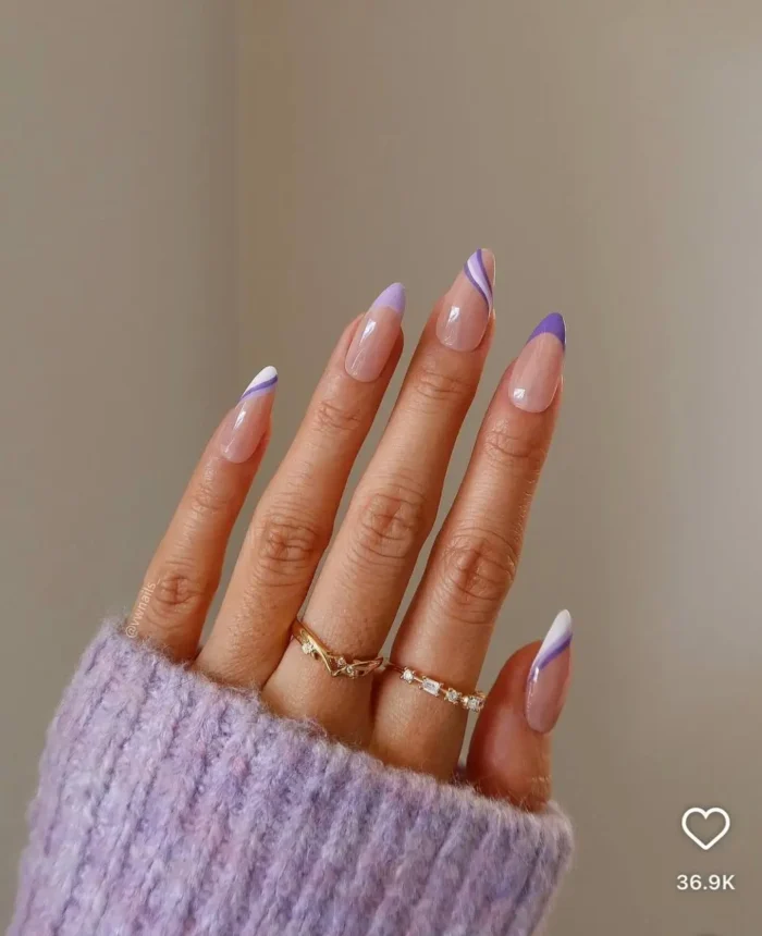 Almond nails with a lavender swirl French purple nail design, featuring modern white wave accents on light purple tips.