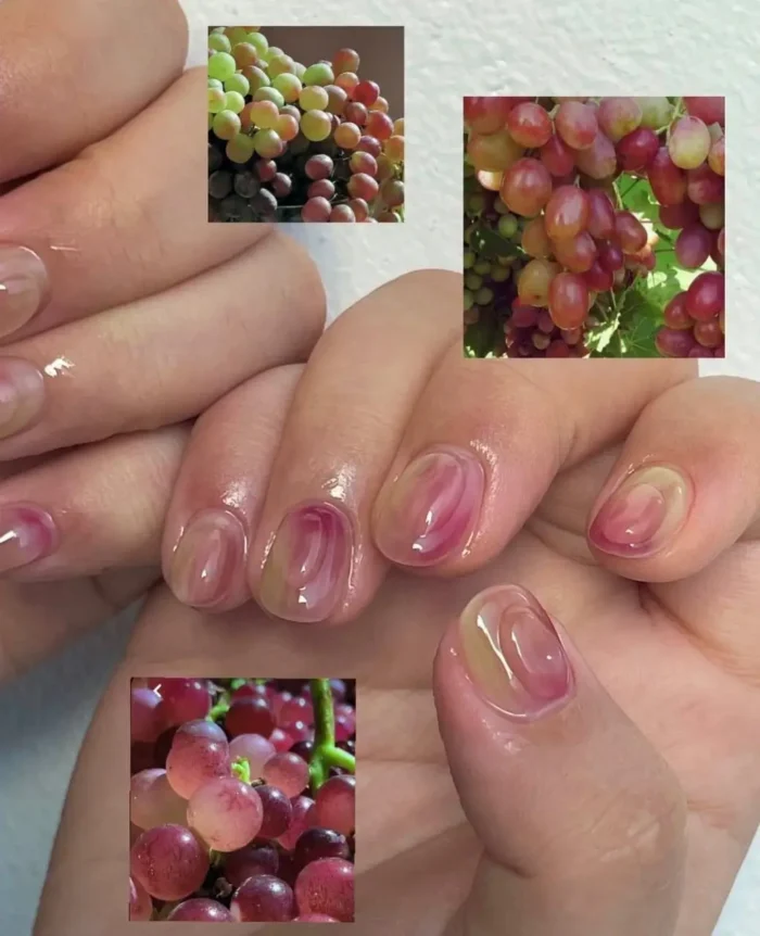A sophisticated grape-inspired manicure on short nails, using translucent watercolor layers of rosé and muted green polish.