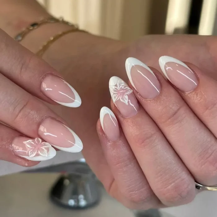 An elegant almond-shaped French manicure with a delicate, semi-translucent 3D white flower on the accent nail.
