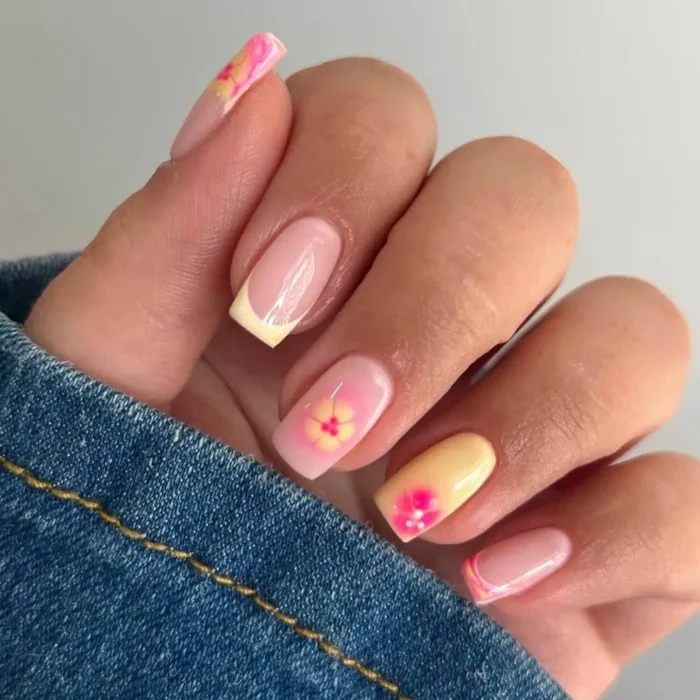 Square-shaped nails featuring a mix of pale yellow French tips and accent nails with pink and yellow plumeria-style flowers.
