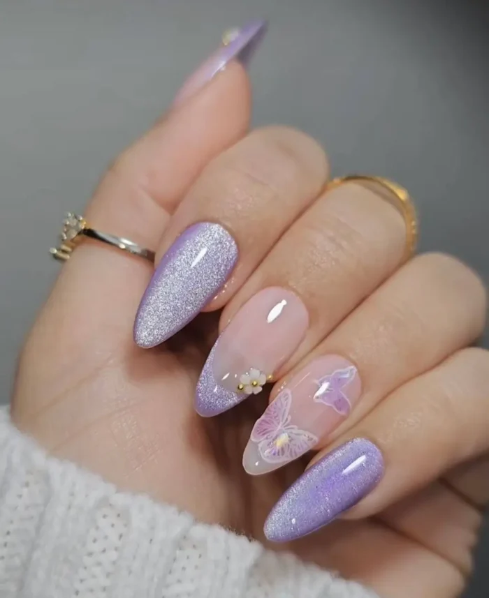 A magical manicure featuring shimmery lavender glitter nails and a lifelike, 3D butterfly accent on a sheer base.