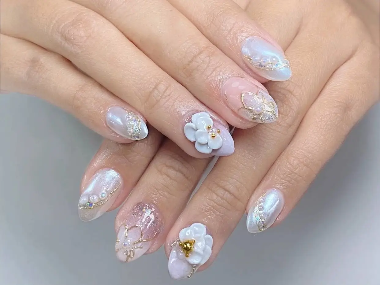 Beautiful nail art design featuring luminous pearlescent white nails with 3D flowers and gold details - thumbnail.
