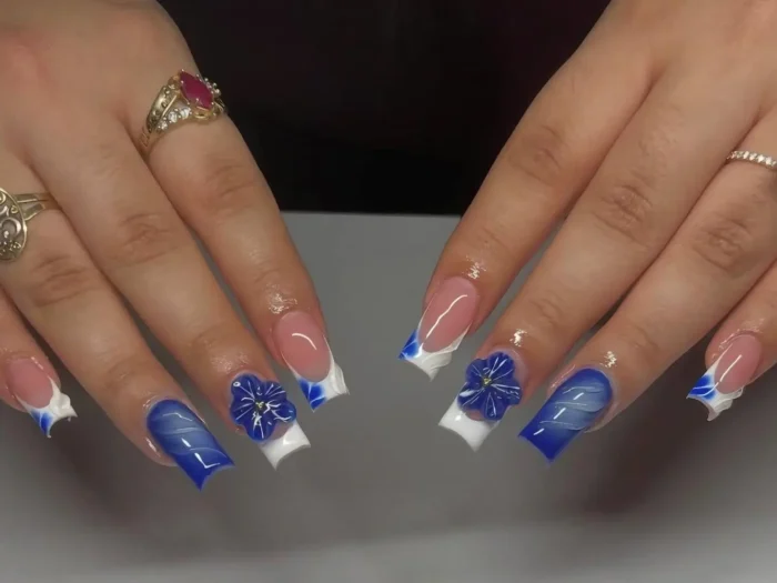 A chic blue flower nail design with a 3D floral accent and crystal details, featured in a gallery of 23 manicure ideas.