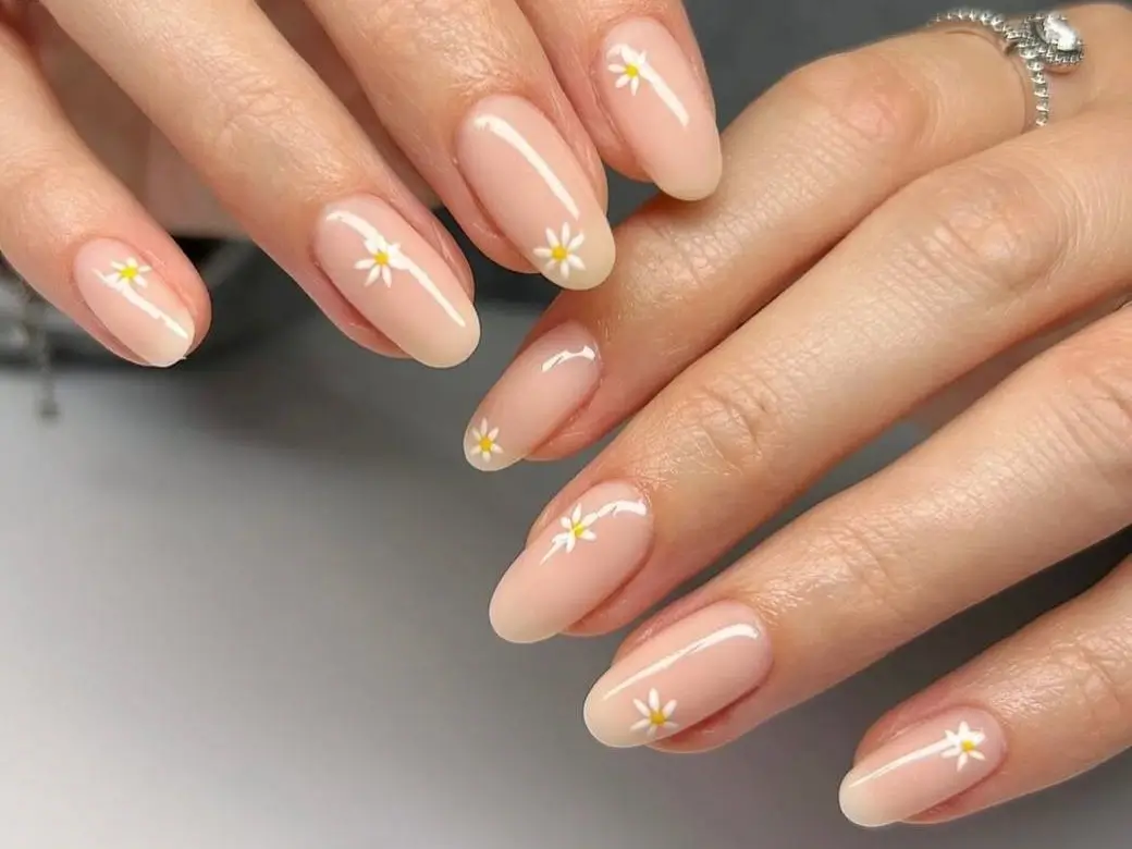 Nude nails with a delicate daisy design, representing a collection of cute simple nail ideas.