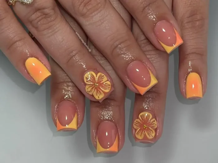 A stunning example of French tip nail design ideas: two-tone orange and yellow tips with intricate 3D floral details.