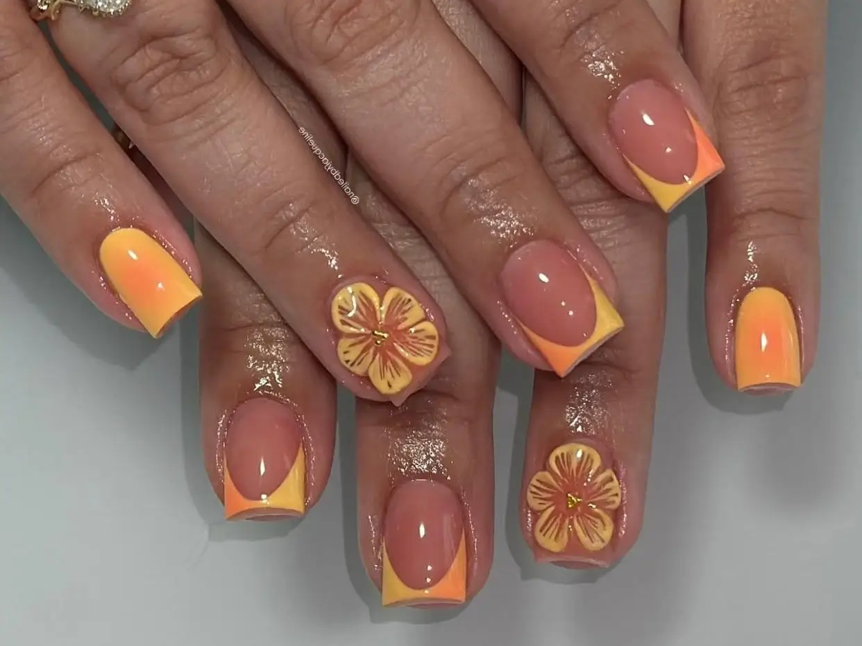 A stunning example of French tip nail design ideas: two-tone orange and yellow tips with intricate 3D floral details.