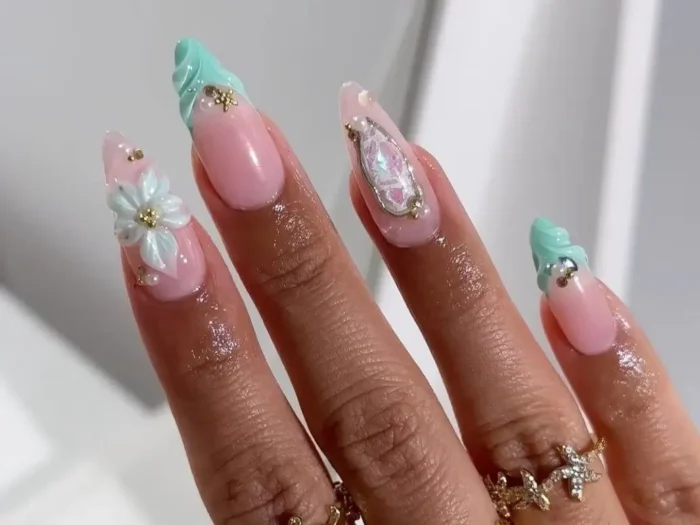 Elegant summer nail art thumbnail: Long almond nails with mint green sculpted tips, a 3D white flower, and iridescent gem accents.