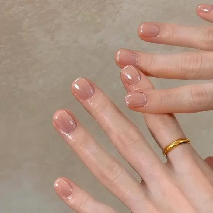 A close-up of hands with short, natural nails wearing only a high-gloss, ultra-sheer polish for a clean look.