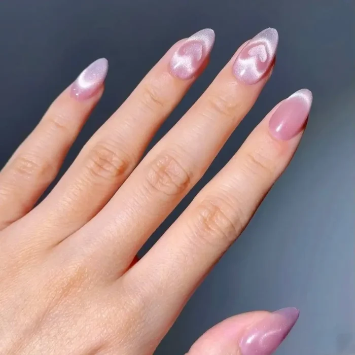 A creative pink cat eye nail design on almond-shaped nails where the magnetic shimmer is formed into a heart shape.