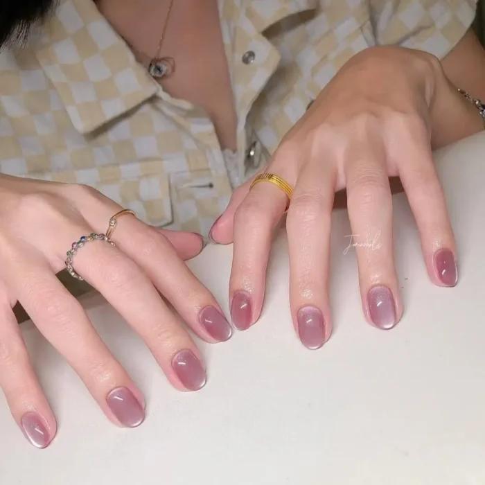 Short nails showcasing a purple-pink cat-eye gel polish with a soft, subtle white French tip.