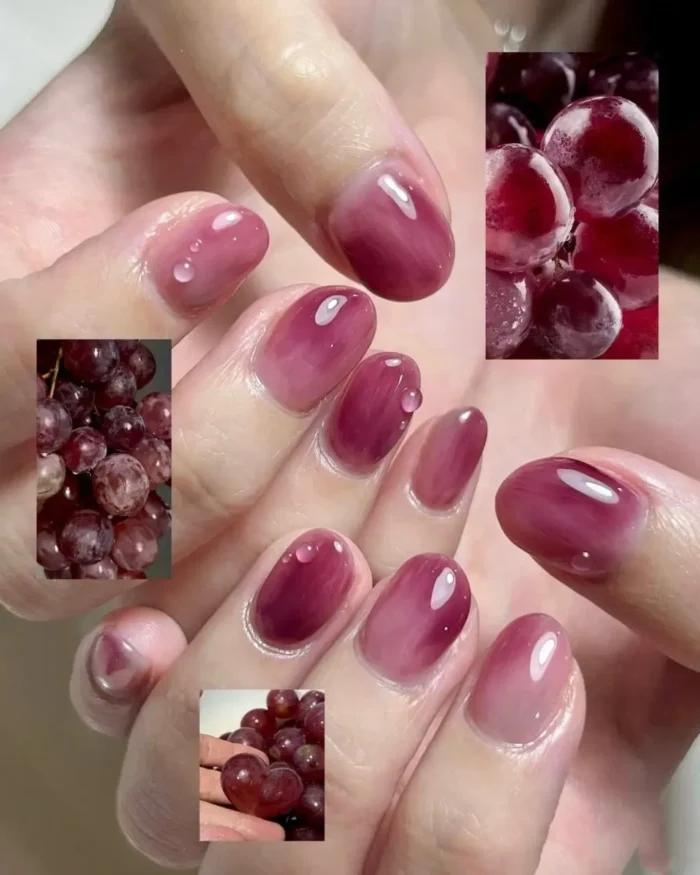 A close-up of a sheer grape-colored manicure with a glossy jelly finish and tiny 3D water droplet accents.