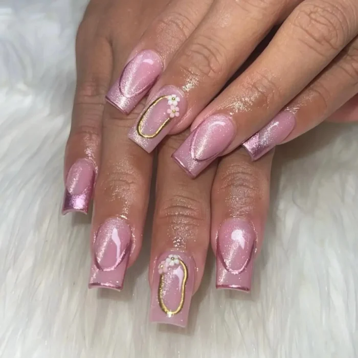 An ornate pink cat eye nail design on long square nails, featuring encapsulated shimmer, gold frames, and 3D floral charms.