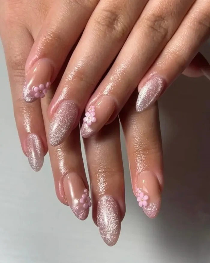 A mixed manicure on almond nails featuring glittery pink cat eye polish and sheer nails with 3D pink flower clusters.