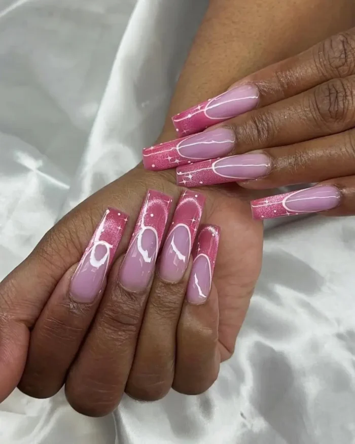 A bold pink cat eye manicure on long square nails, featuring graphic white heart outlines and sparkling tips.