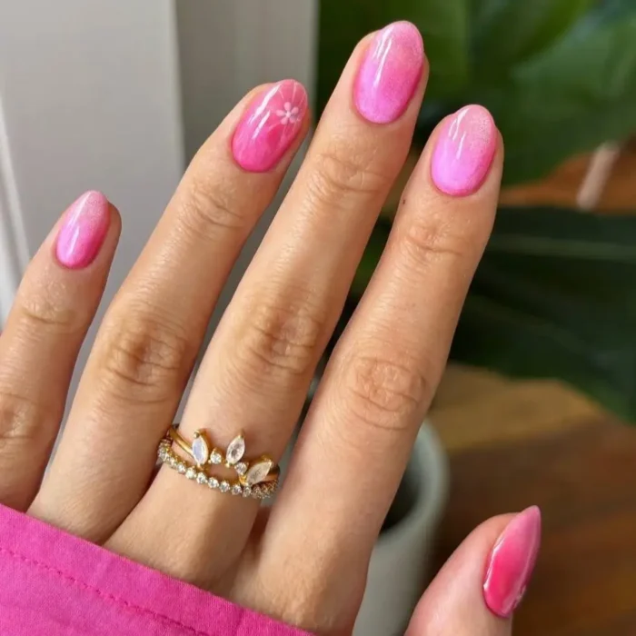 Short, oval nails painted in a bright, shimmering pink gel polish, giving off a soft glow and subtle metallic effect.