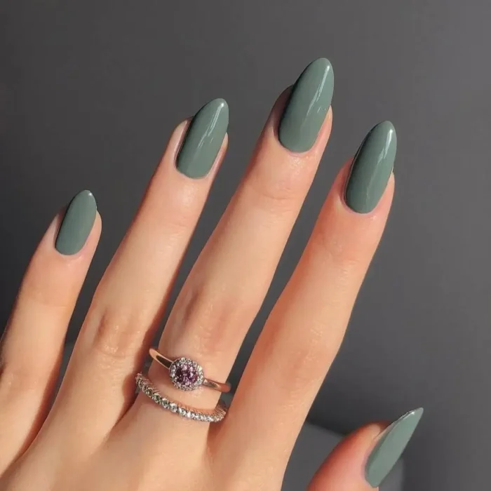 A hand with long, elegant almond-shaped nails painted in a glossy, dusty eucalyptus green.