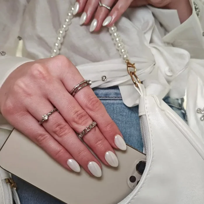 An elegant white nail design on almond-shaped nails with a high-shine, polished pearl finish.